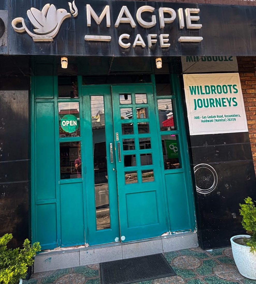 The teal front doors and Magpie Cafe sign by day