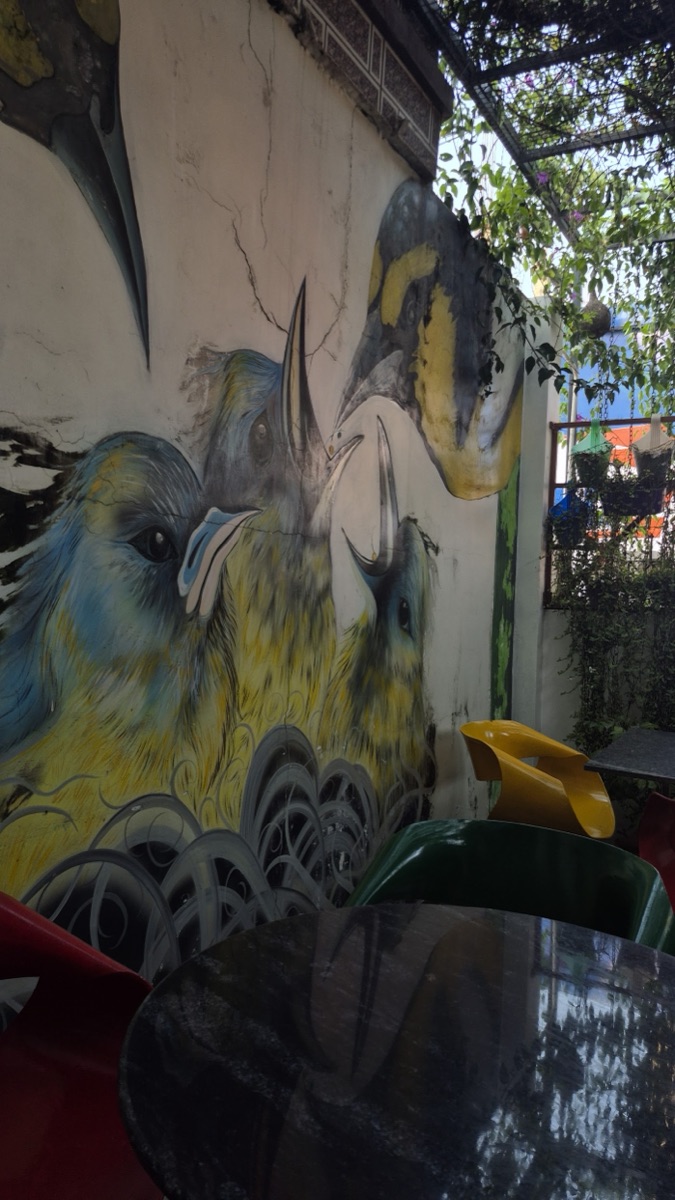 A large painted bird mural on the wall of the outdoor seating area