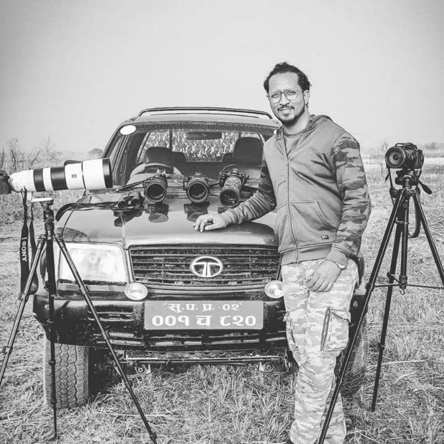 Deepankar Khulbe standing beside a safari vehicle with cameras and long lenses set up in a grassland